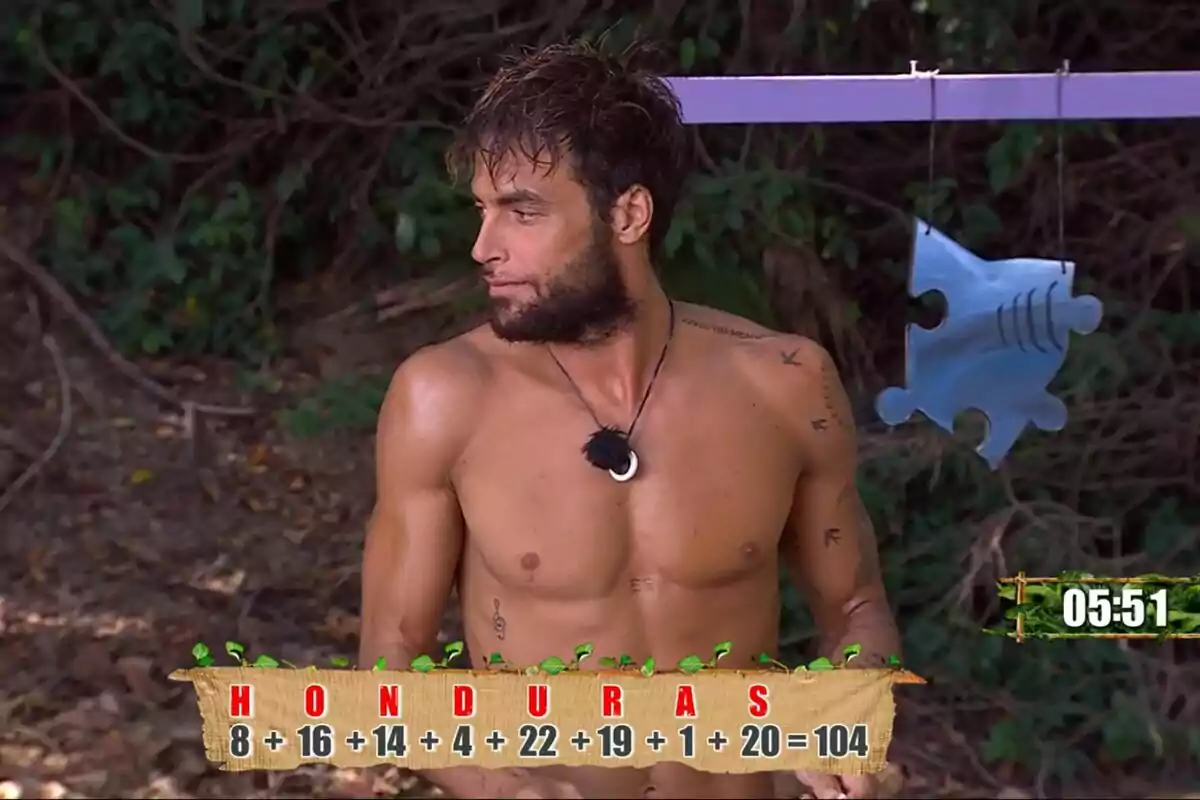 Montoya sin camisa con barba y tatuajes está de pie en un entorno selvático con un rompecabezas colgante y un cronómetro que marca 05:51 en Supervivientes. Montoya sin camisa con barba y tatuajes está de pie en un entorno selvático con un rompecabezas colgante y un cronómetro que marca 05:51 en Supervivientes.