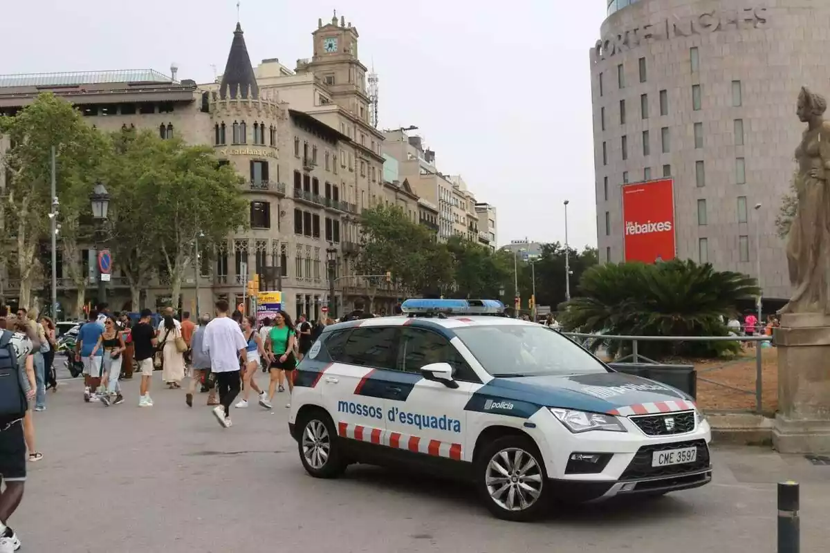 Plano general de la plaza Cataluña de Barcelona con un coche de los Mossos en primer plano