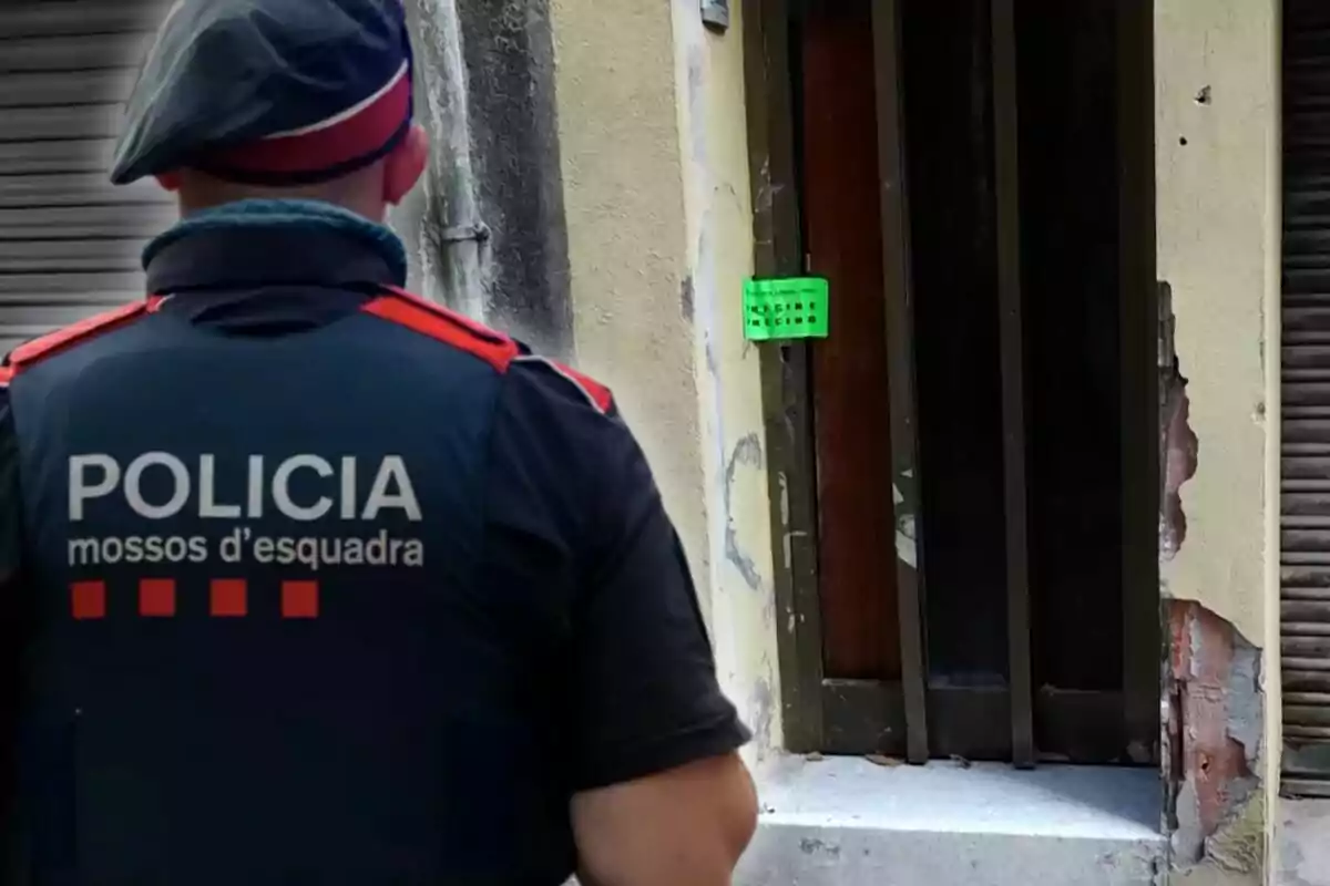 Un agente de los Mossos d'Esquadra frente a una puerta con un cartel verde.