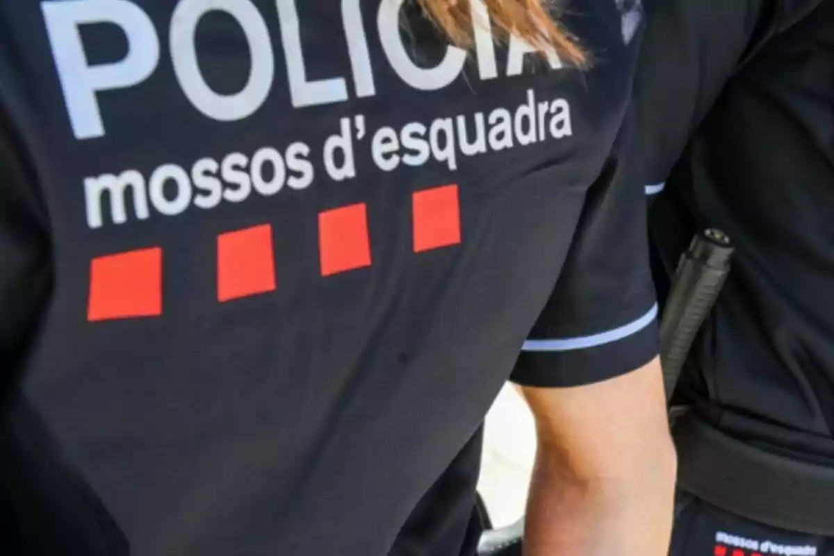 Uniforme de un agente de los Mossos d'Esquadra con la palabra "POLICIA" y cuatro cuadrados rojos.