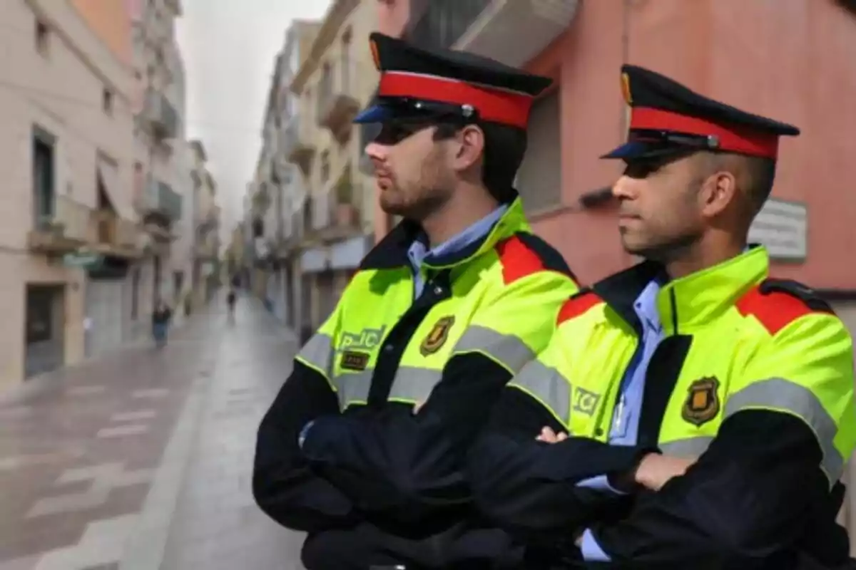 Dos policías con uniformes de alta visibilidad observan una calle urbana.