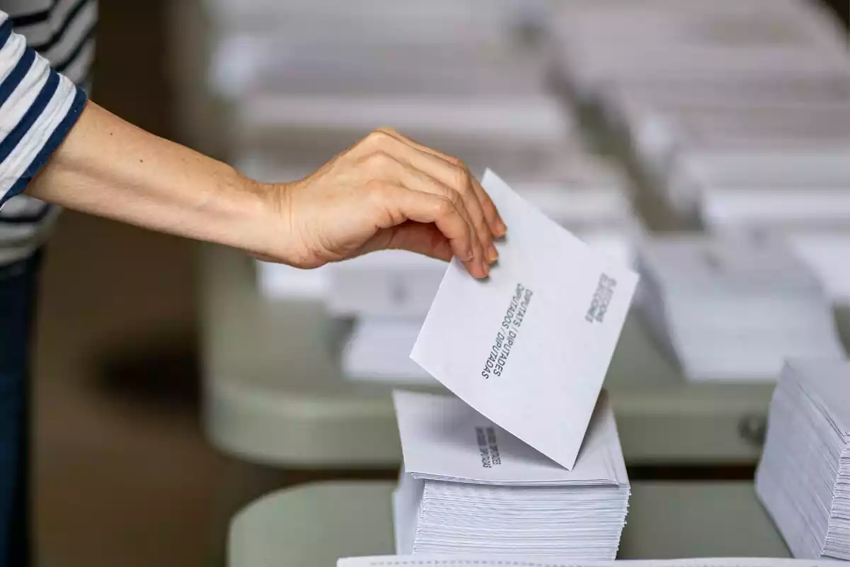 Una mujer escogiendo un sobre para las elecciones catalanas