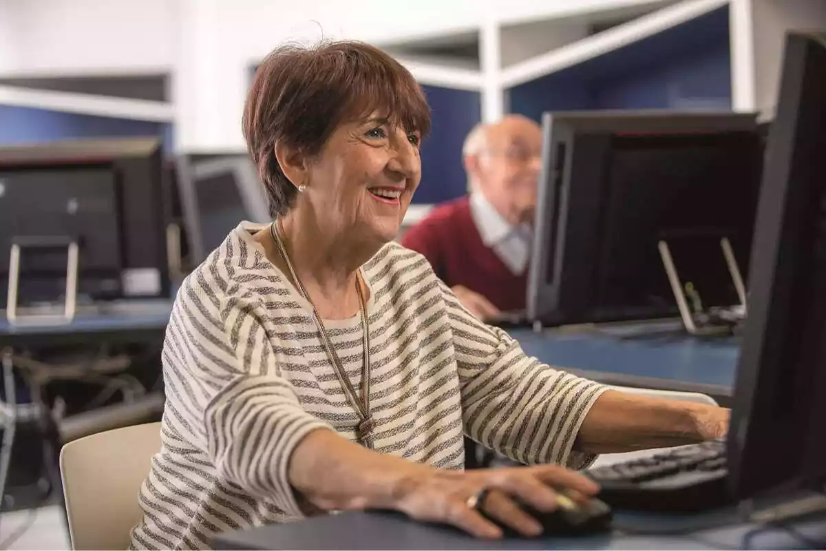 Mujer mayor sonriendo y utilizando un ordenador