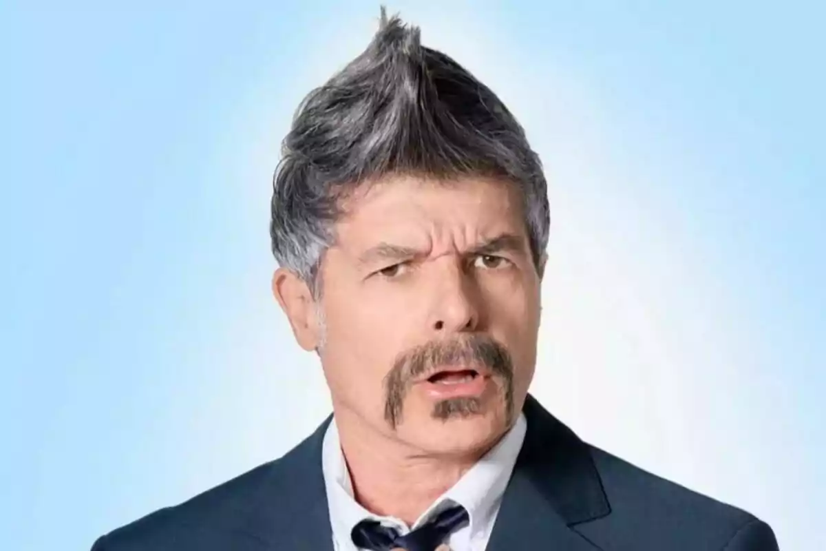 Hombre con bigote y peinado puntiagudo vestido con traje y corbata sobre fondo azul claro Hombre con bigote y peinado puntiagudo vestido con traje y corbata sobre fondo azul claro