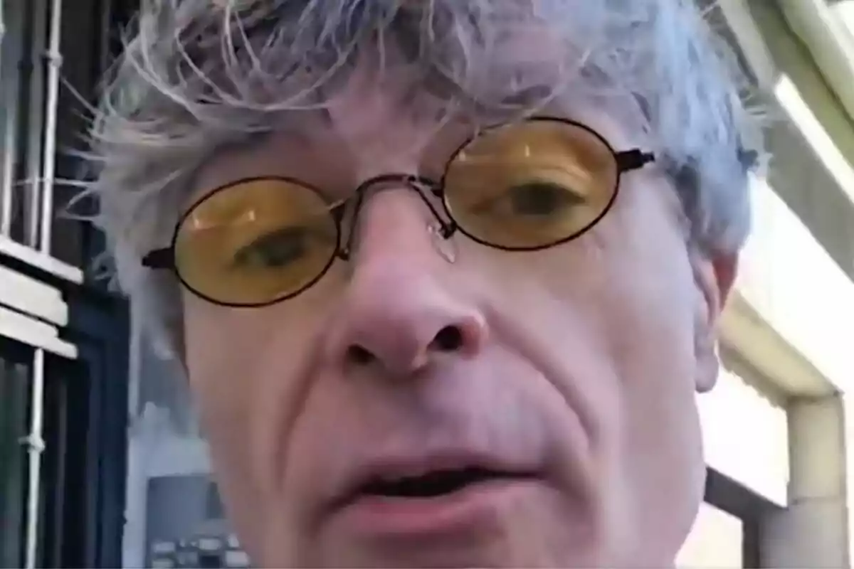 Hombre de cabello canoso usando gafas con lentes amarillos en un entorno urbano.