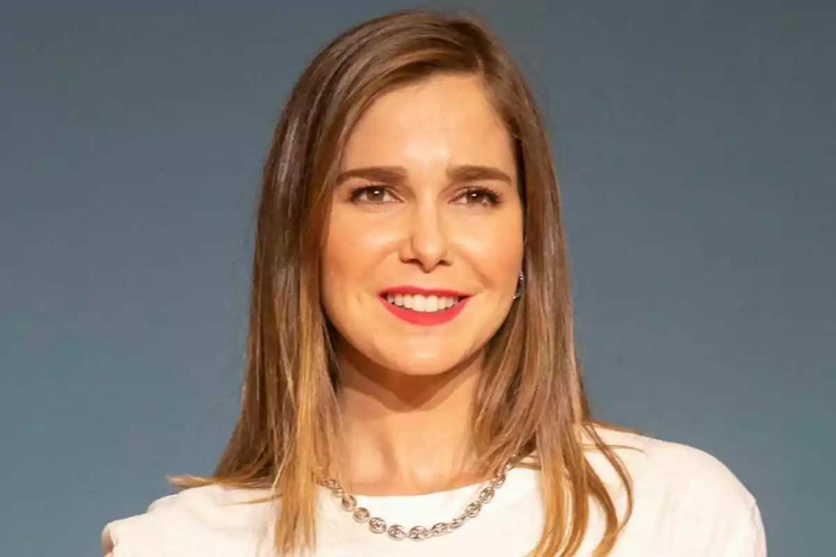 Natalia Sánchez con cabello castaño sonríe frente a un fondo azul en el photocall de Regreso a las Sabinas.