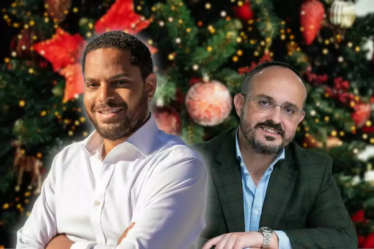 Dos hombres sonrientes posan frente a un árbol de Navidad decorado.