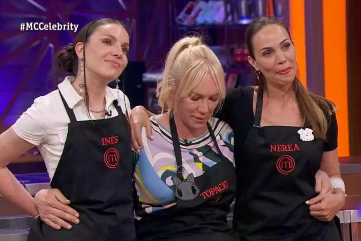 Nerea Garmendia, Inés Hernand y Topacio Fresh con delantales de "MasterChef Celebrity" se abrazan en un set de cocina.