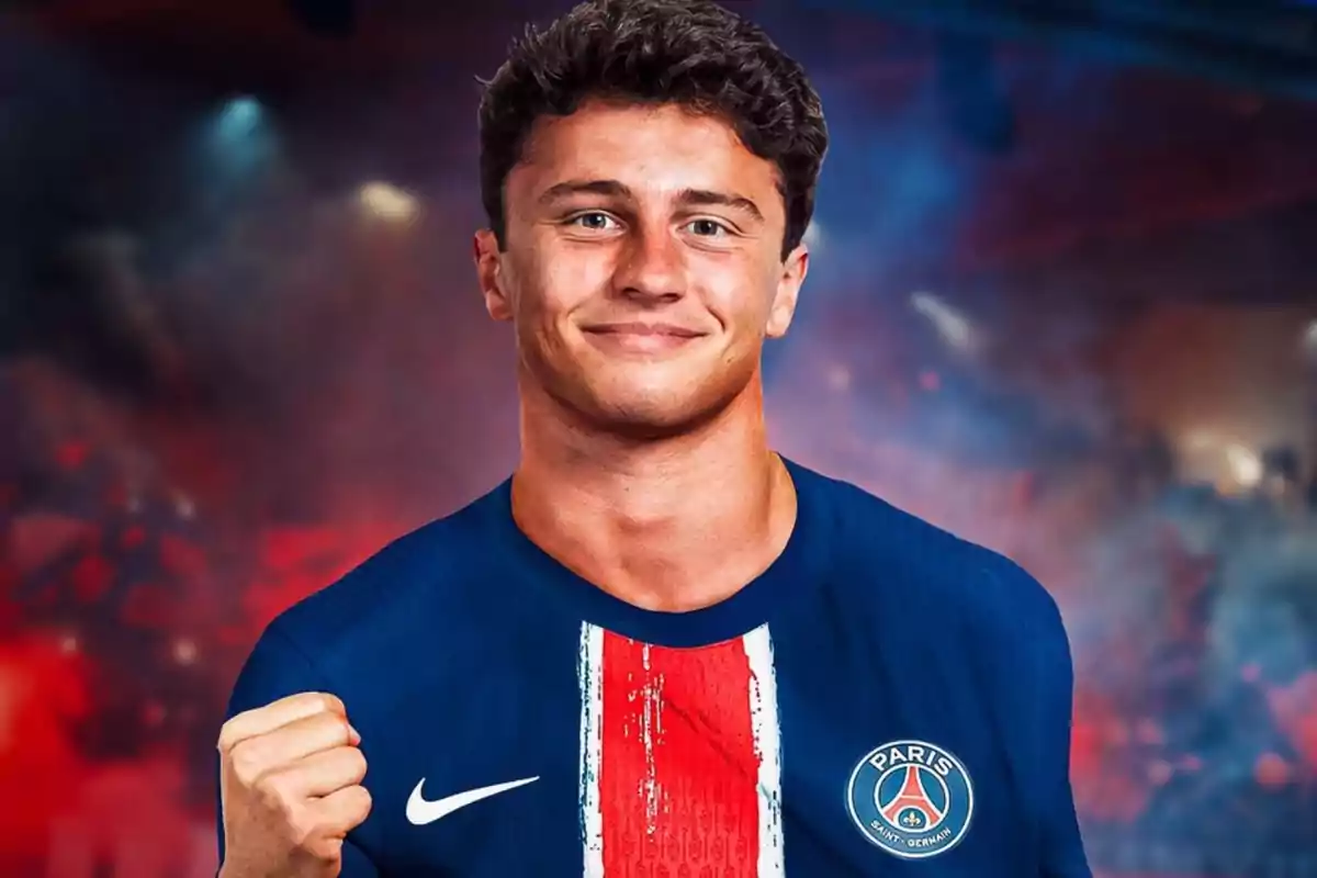 Un joven con una camiseta del Paris Saint-Germain sonríe y levanta el puño en señal de celebración, con un fondo difuminado de colores oscuros y luces. Un joven con una camiseta del Paris Saint-Germain sonríe y levanta el puño en señal de celebración, con un fondo difuminado de colores oscuros y luces.