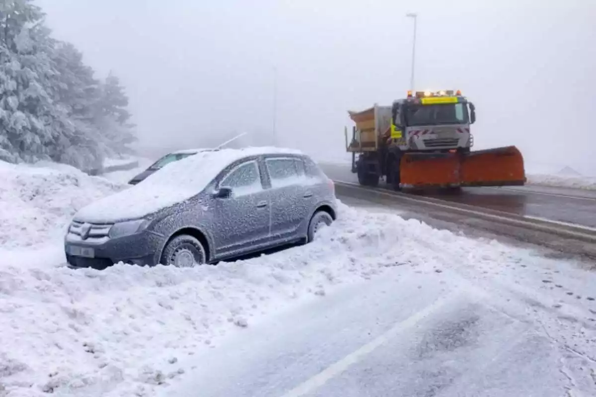 Una quitanieve circula por la carretera, con un coche cubierto de nieve