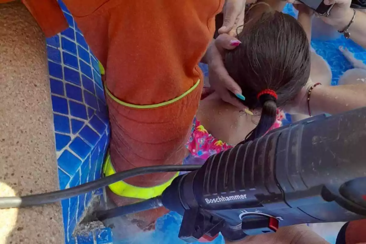 Bomberos rescatando a una niña atrapada en una piscina