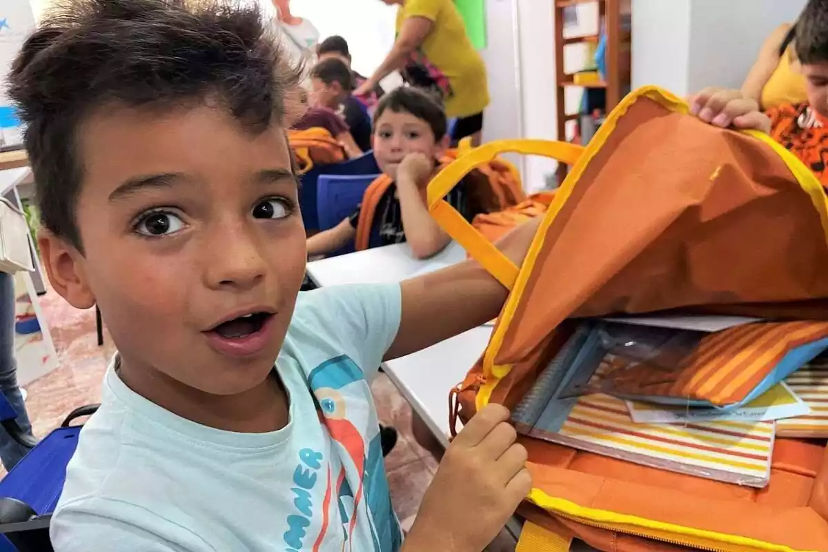 Un niño, con cara de sorpresa, abriendo su mochila escolar