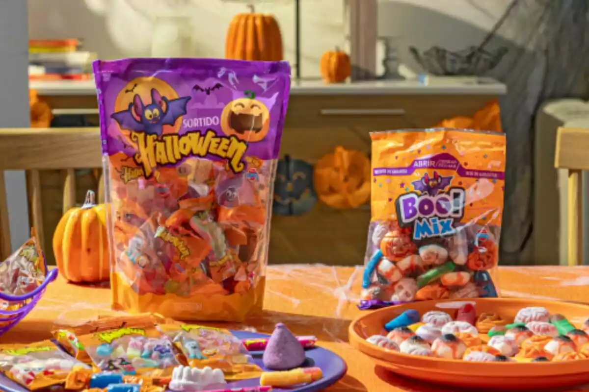 Una mesa decorada para Halloween con bolsas de dulces y golosinas temáticas, rodeada de calabazas y adornos festivos. Una mesa decorada para Halloween con bolsas de dulces y golosinas temáticas, rodeada de calabazas y adornos festivos.