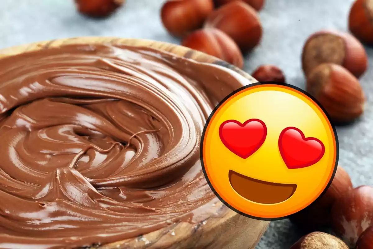 Emoji con corazones en los ojos sobre imagen en plano junto a unas cuantas avellanas de talle de cuenco de madera con chocolate para untar tipo Nutella