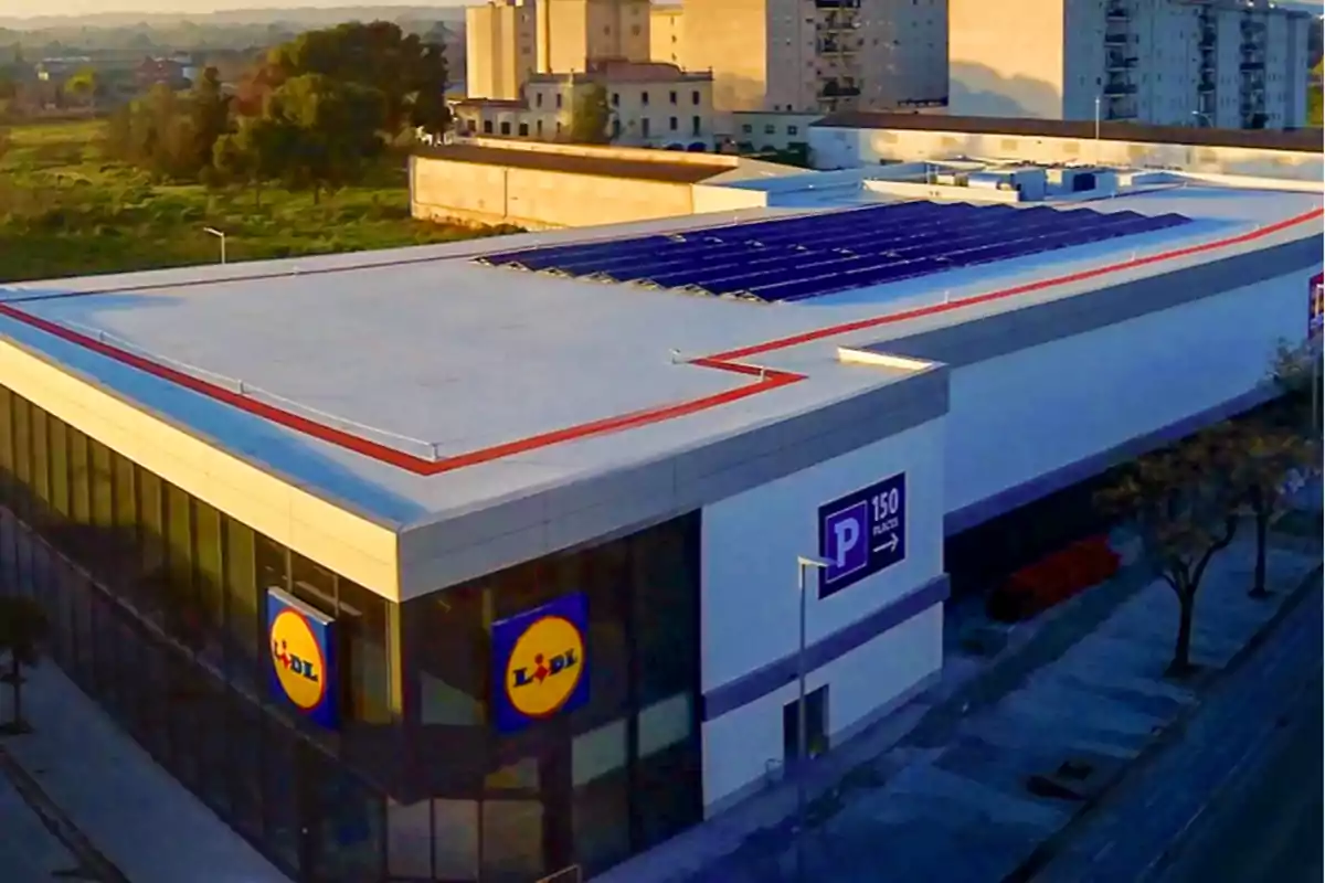 Vista aérea de un supermercado con paneles solares en el techo y un cartel que indica 150 plazas de estacionamiento. Vista aérea de un supermercado con paneles solares en el techo y un cartel que indica 150 plazas de estacionamiento.