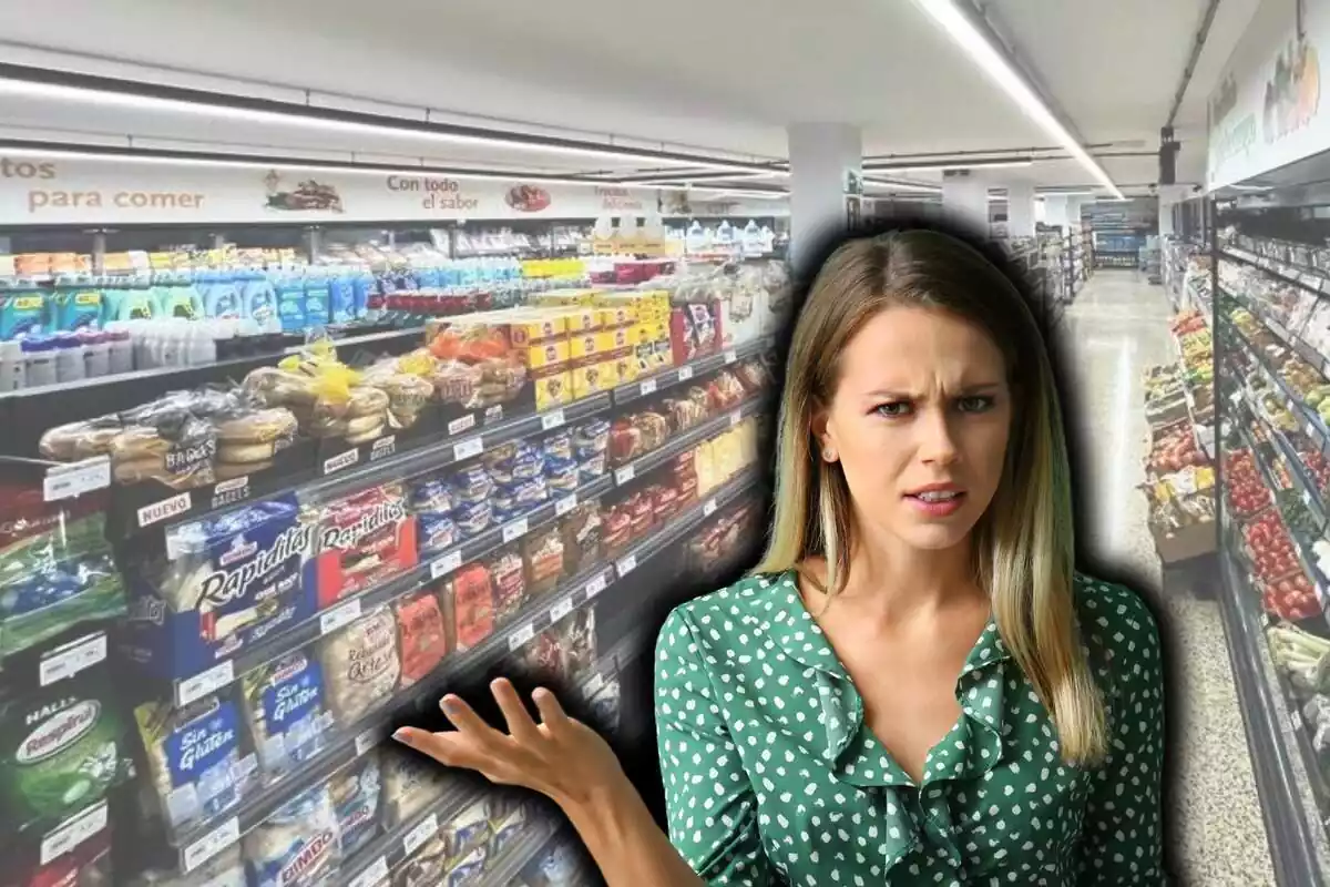 Mujer rubia de pecho para arriba con camisa verde de volantes y gesto indignado con la palma de una mano hacia arriba, sobre fondo de supermercado