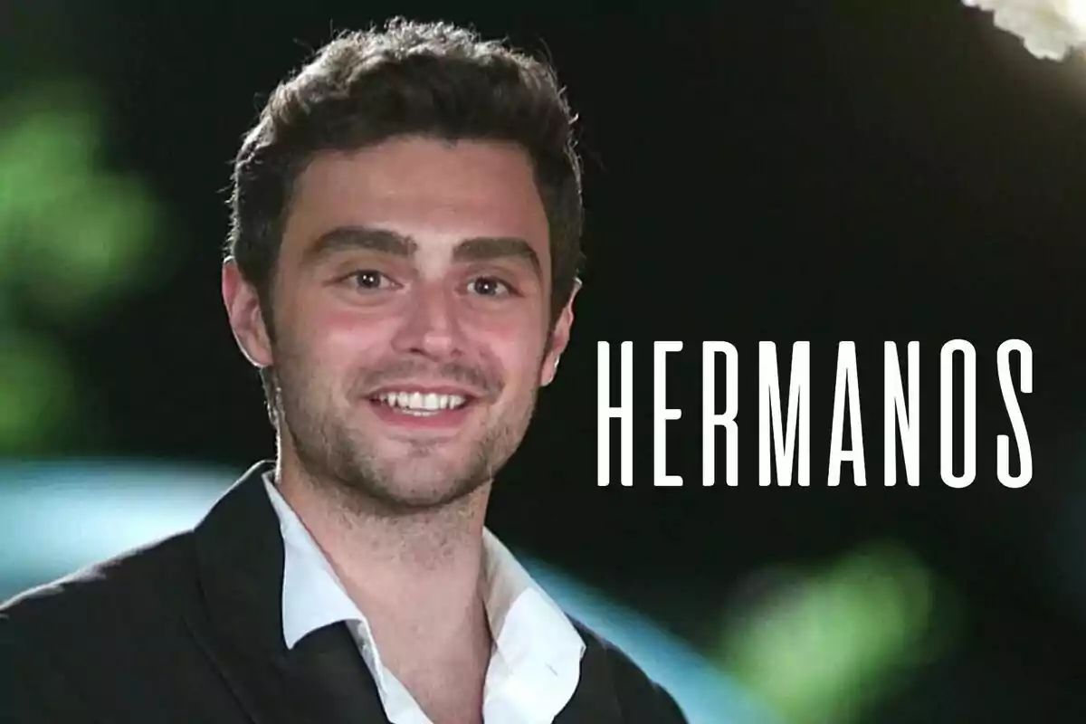 Ömer sonriente con barba y cabello oscuro lleva una camisa blanca y un saco negro, con la palabra "HERMANOS" escrita al lado.