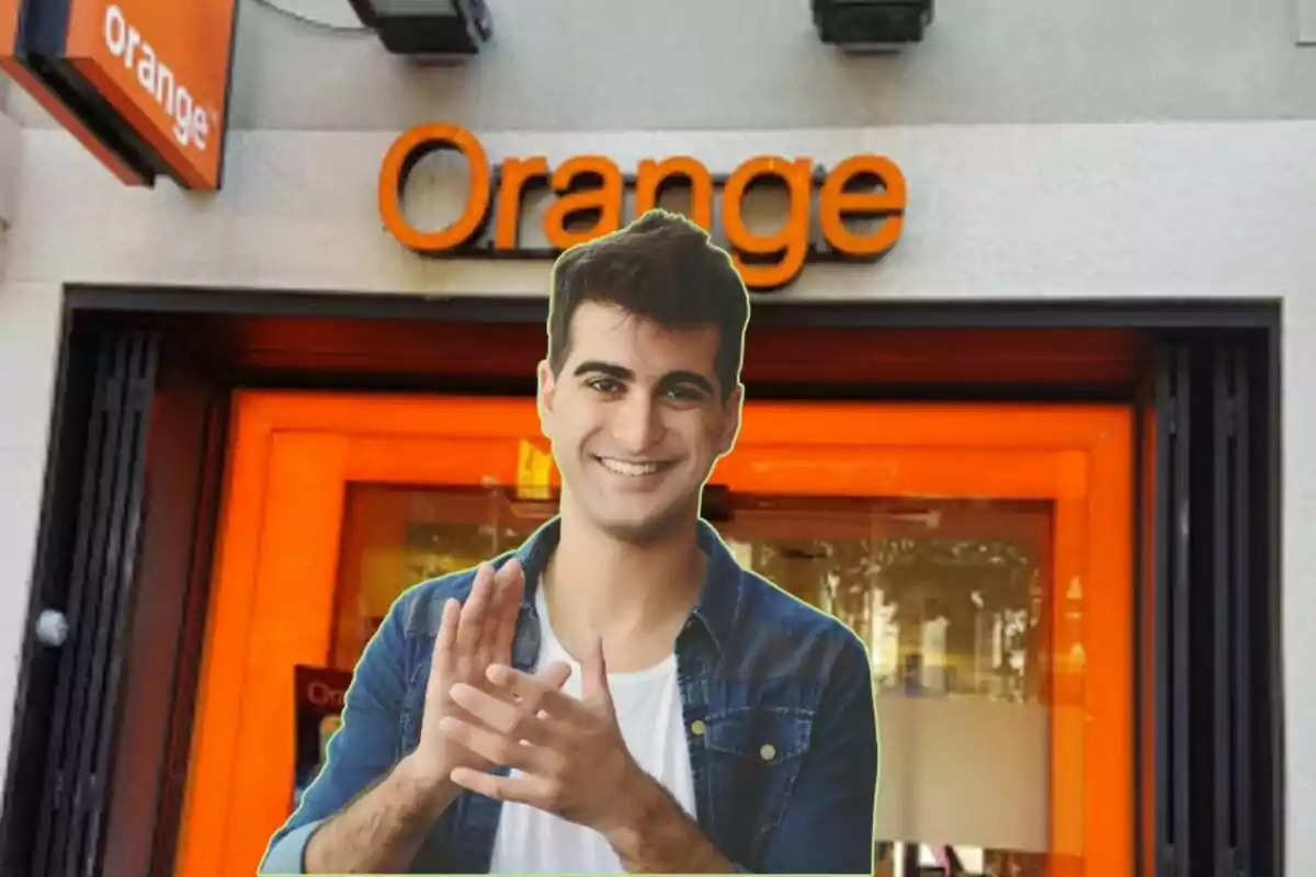 Un hombre sonriente con una camisa de mezclilla está frente a una tienda de Orange.