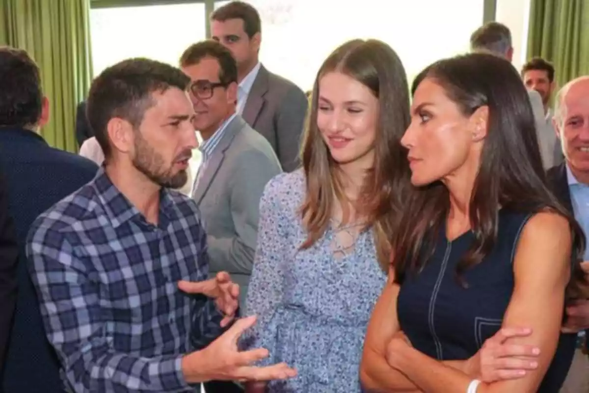 Un hombre con una camisa de cuadros hablando efusivamente con la reina Letizia y la princesa Leonor