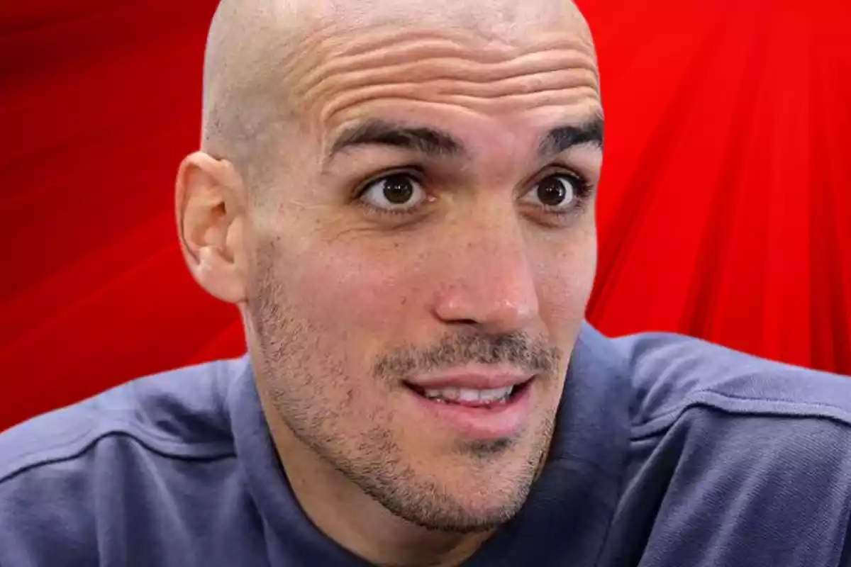 Oriol Romeu en primer plano con cara de sorpresa al lado de un fondo rojo