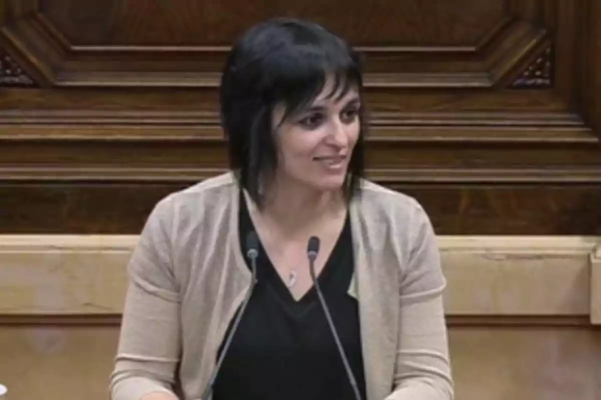 Sílvia Orriols hablando en el atril del Parlament con micrófonos en un entorno de madera.
