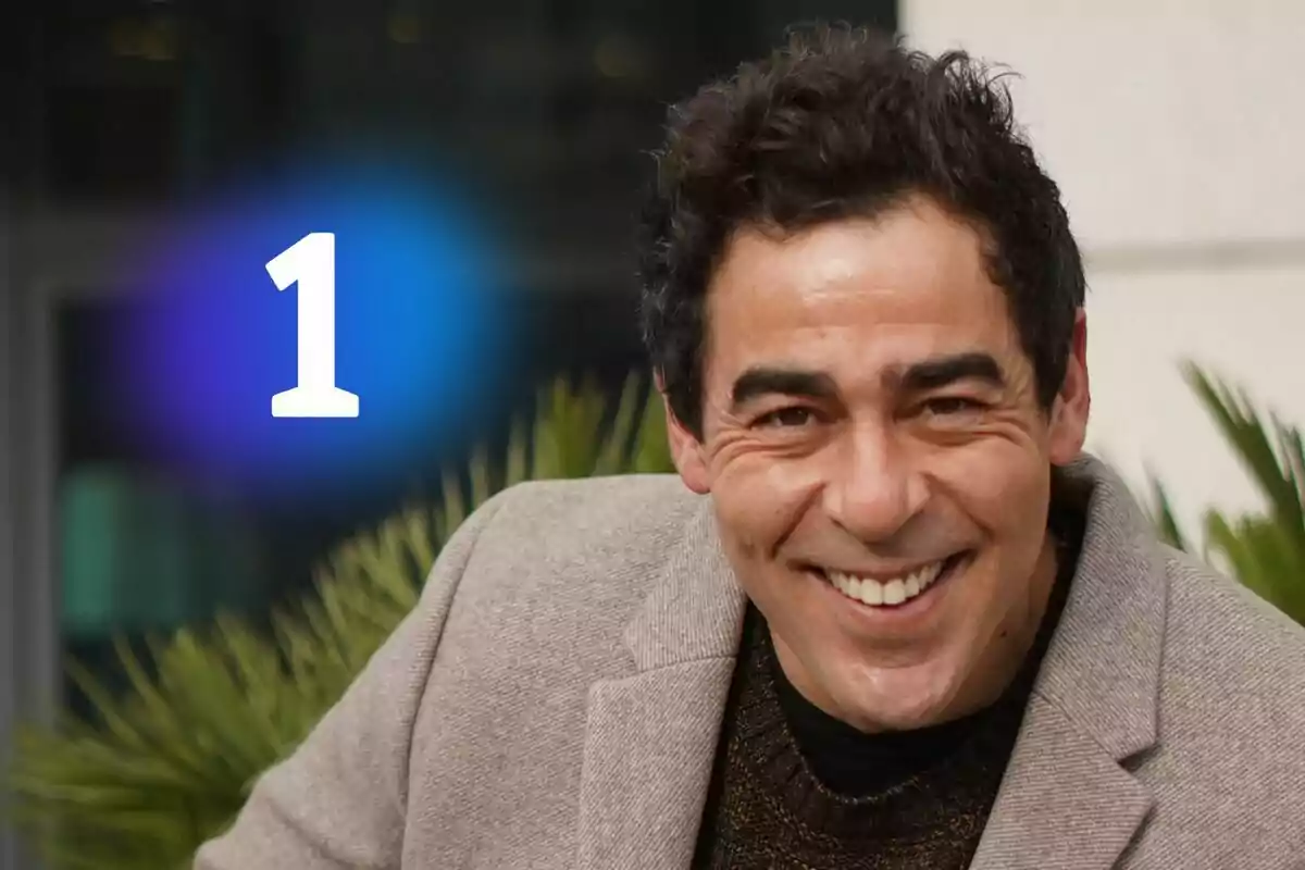 Pablo Chiapella sonriente con cabello oscuro y saco beige, el logo de La 1 grande en color blanco sobre un resplandor azul