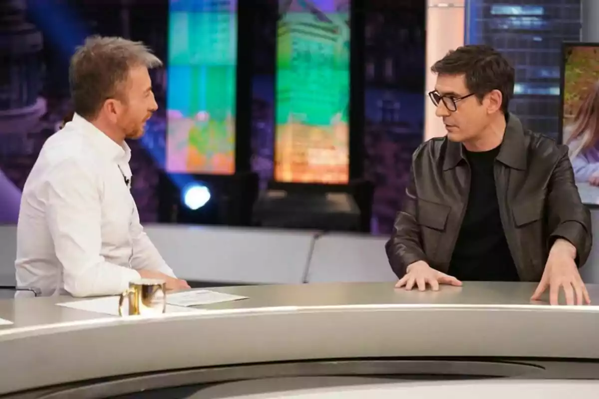 Juanra Bonet y Pablo Motos conversando en 'El Hormiguero' con pantallas coloridas de fondo. Juanra Bonet y Pablo Motos conversando en 'El Hormiguero' con pantallas coloridas de fondo.