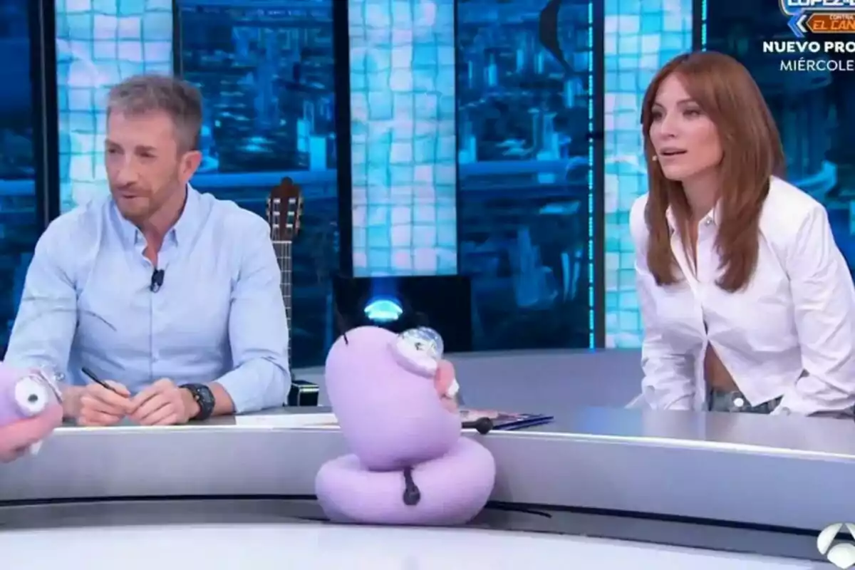 Pablo Motos junto a Edurne sentadas en el plató de El Hormiguero con marionetas moradas sobre la mesa.