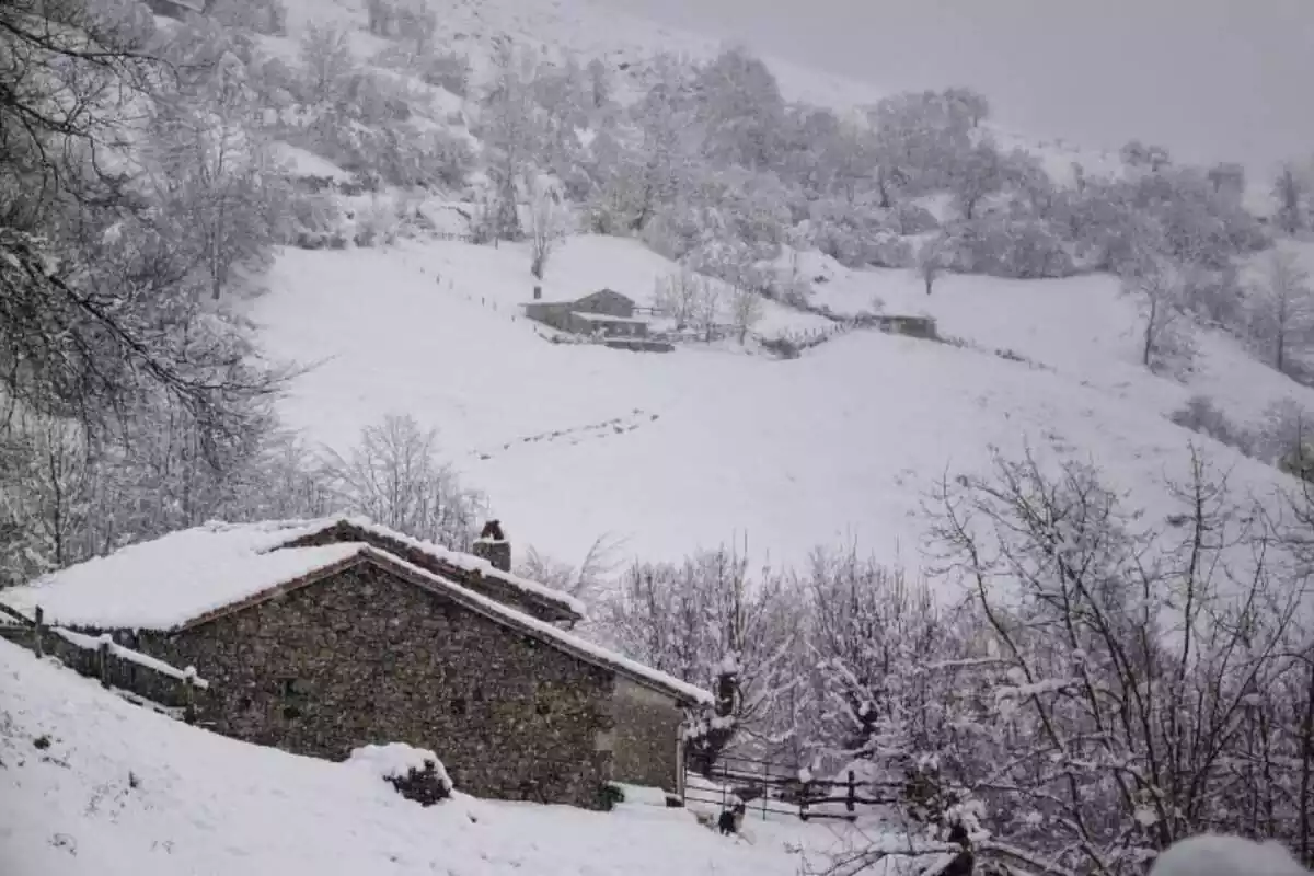 Imagen panorámica de una casa en medio de la montaña durante una intensa nevada