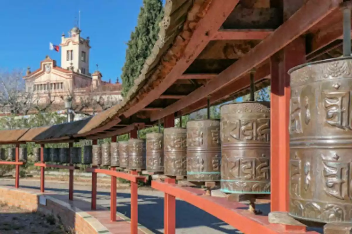 Ruedas de oración tibetanas en un templo con un edificio histórico al fondo. Ruedas de oración tibetanas en un templo con un edificio histórico al fondo.