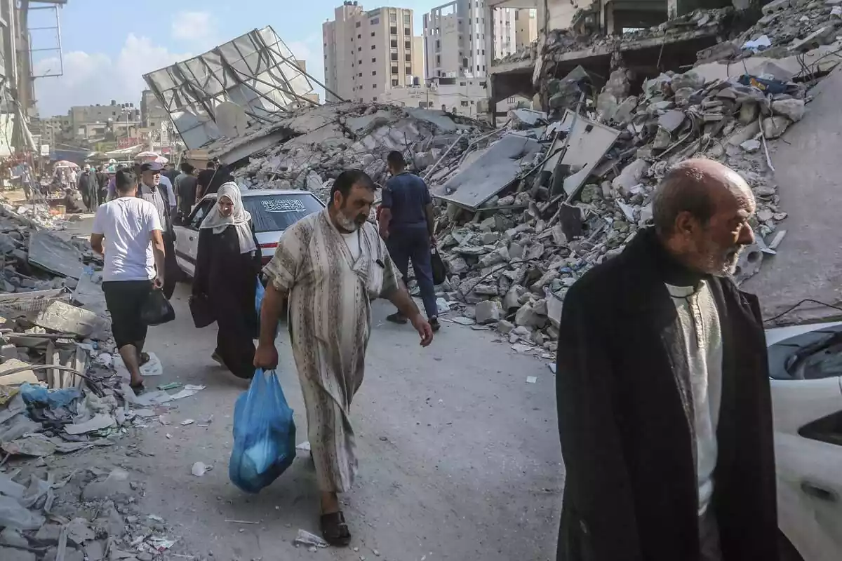 Los palestinos pasan junto a los restos de los edificios destruidos por los ataques aéreos israelíes en Khan Yunis. Cientos de miles de palestinos huyen al sur de la Franja de Gaza para evitar una esperada invasión terrestre israelí, los suministros esenciales se están agotando