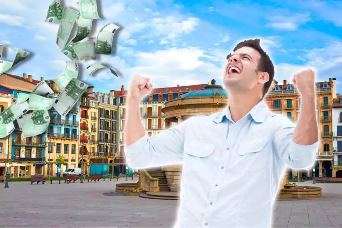 Hombre celebrando con billetes de euro volando en una plaza con edificios coloridos de fondo.