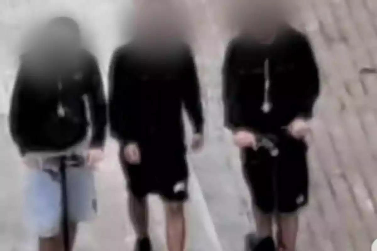 Tres personas caminando por una calle con sus rostros desenfocados.