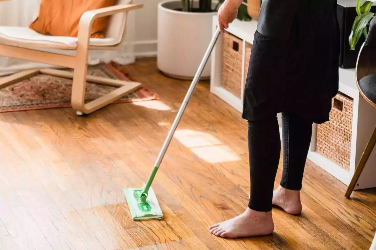 Una persona descalza pasando la mopa por el suelo de una casa