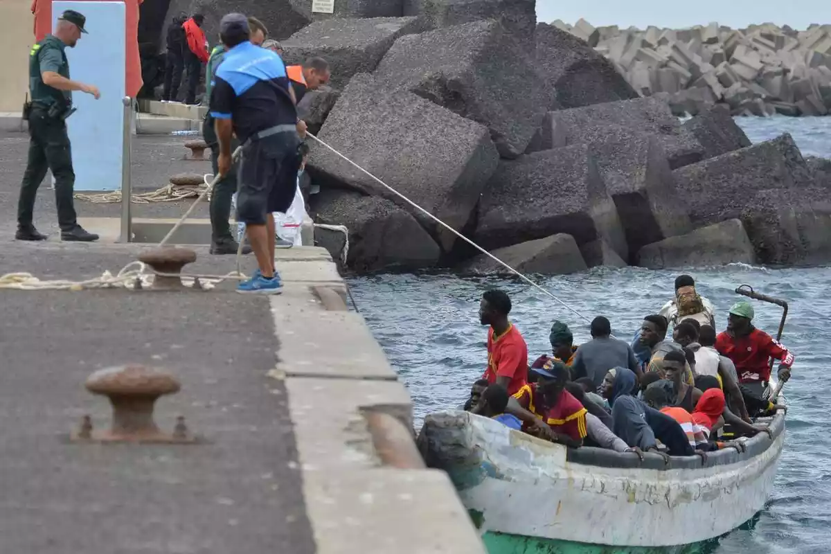 Unos guardias civiles, des de el puerto de Hierro (Canarias) arrastran con una cuerda una patera llena de inmigrantes subsaharianos