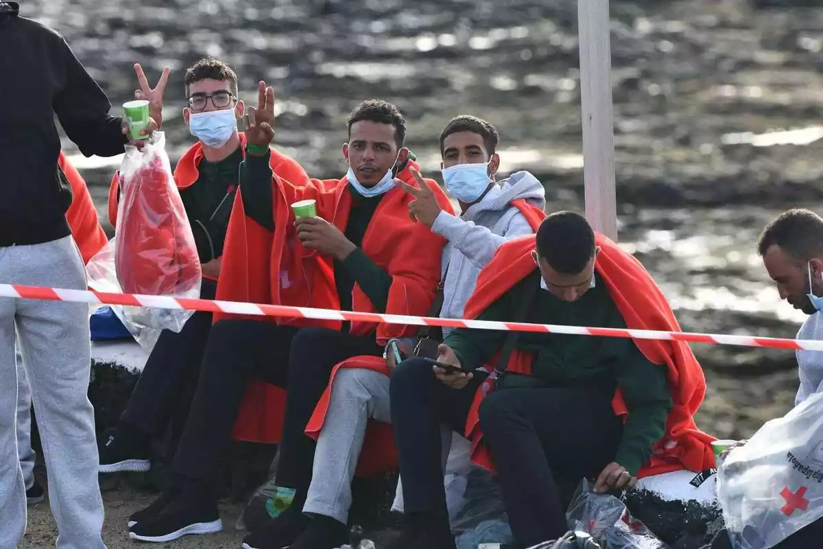 Tres inmigrantes llegados en patera son atendidos por la Cruz Roja y saludan a cámara con el gesto de victoria con la mano