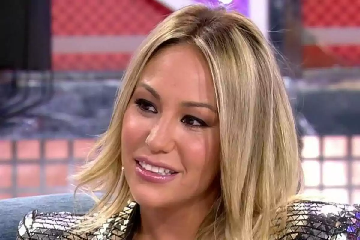 Patricia Steisy rubia con cabello lacio y maquillaje sutil, sonriendo y mirando hacia un lado en un entorno interior en el Deluxe.