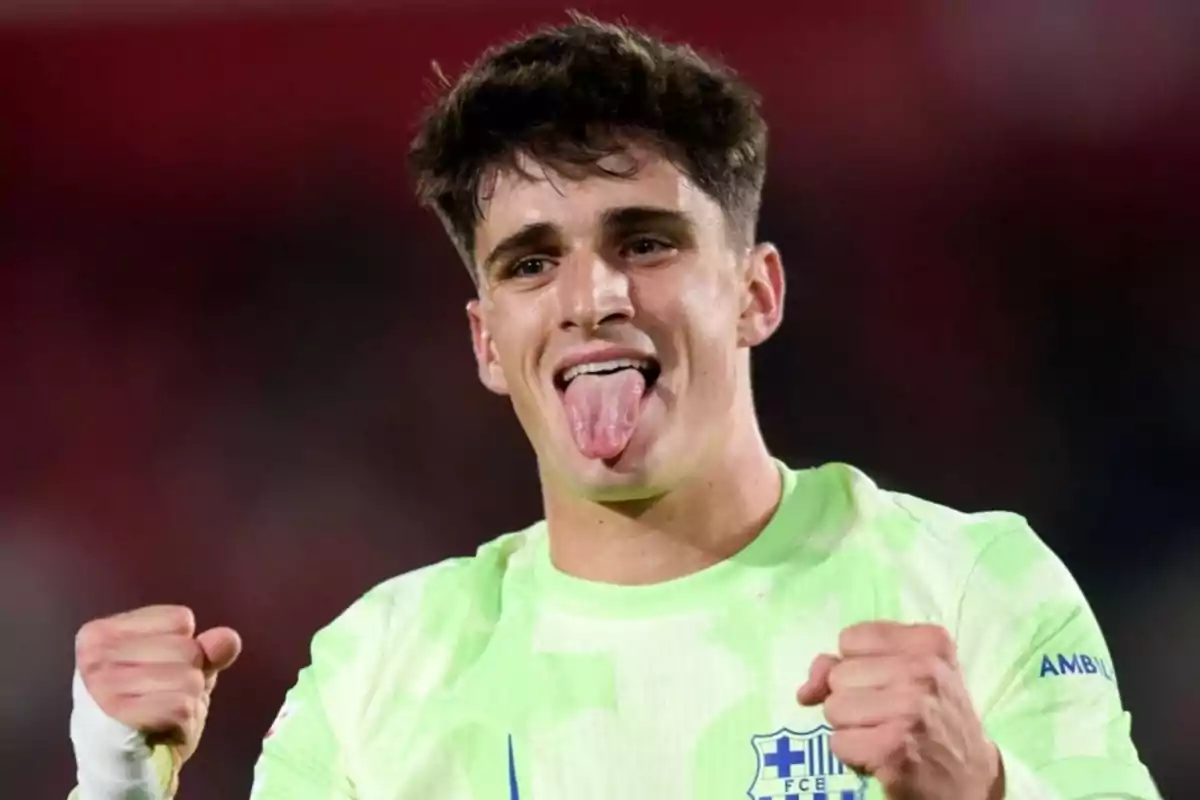 Joven futbolista celebrando con los puños cerrados y sacando la lengua, vistiendo un uniforme verde claro del FC Barcelona