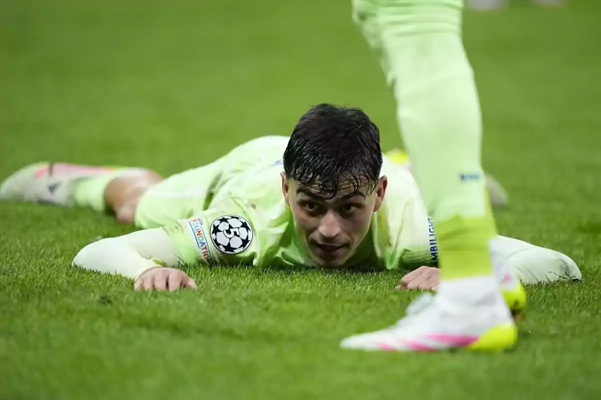 Un jugador de fútbol con uniforme verde claro está tumbado en el césped durante un partido. Un jugador de fútbol con uniforme verde claro está tumbado en el césped durante un partido.
