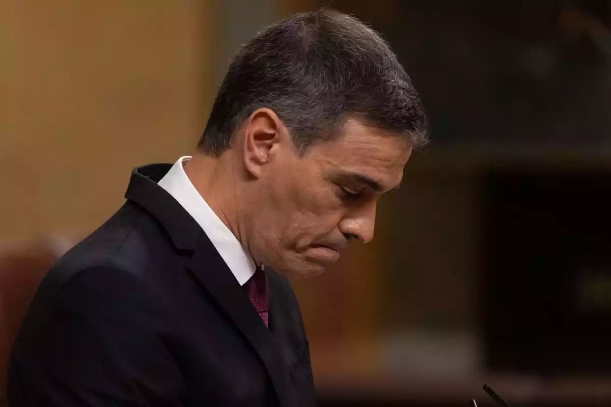 Plano medio cort de Pedro Sánchez en la tribuna del Congreso mirando hacia abajo con cara de preocupación