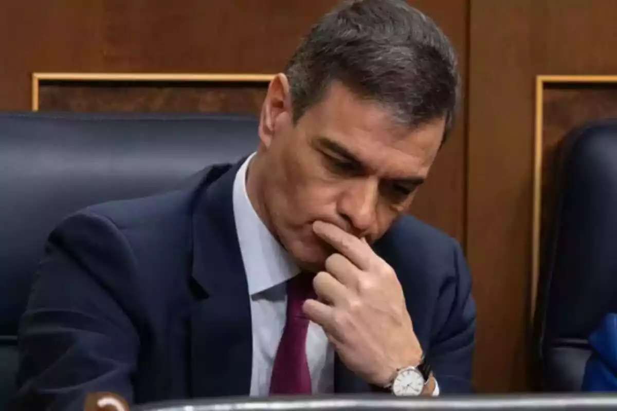 Pedro Sánchez sentado en el congreso con expresión pensativa y mirando hacia abajo