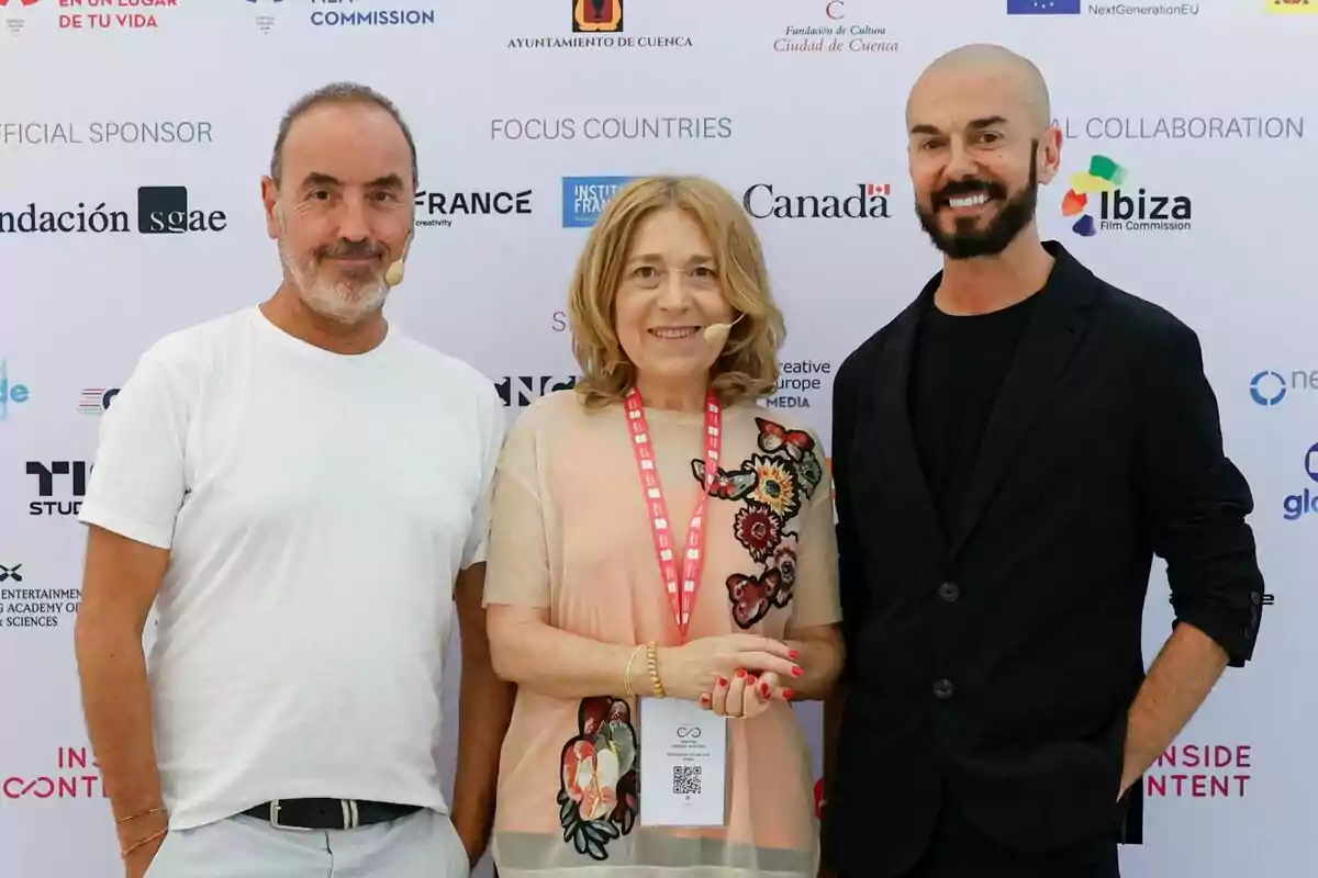 Montse Besada, Gorka García y Oriol Sala-Patau personas posan sonrientes frente a un fondo con logotipos de patrocinadores y colaboradores en un evento