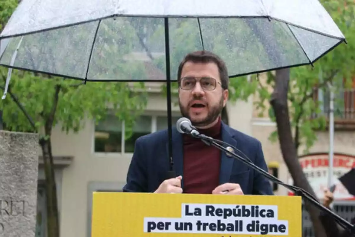 Fotografía de Pere Aragonès en un mítin aguantando un paraguas bajo la lluvia