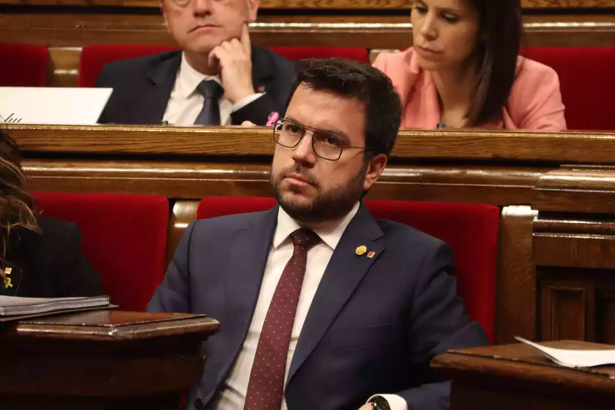 Pere Aragonès con rostro muy serio sentado en su silla del Parlamento de Cataluña