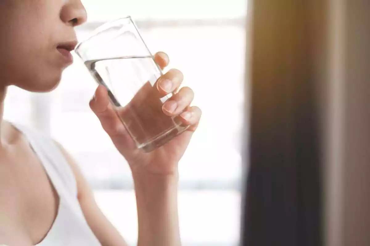 Media cara de una mujer bebiendo agua