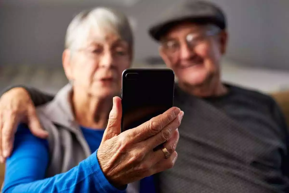 Dos personas mayores mirando la pantalla de un móvil