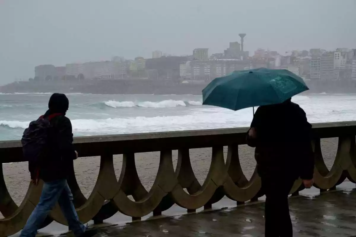 Dos personas caminando por un paseo marítimo en Galicia