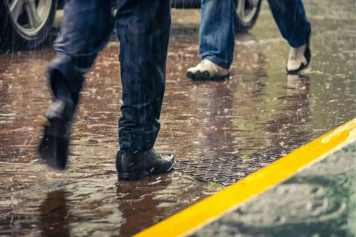 Piernas de gente caminando por la calle mientras llueve