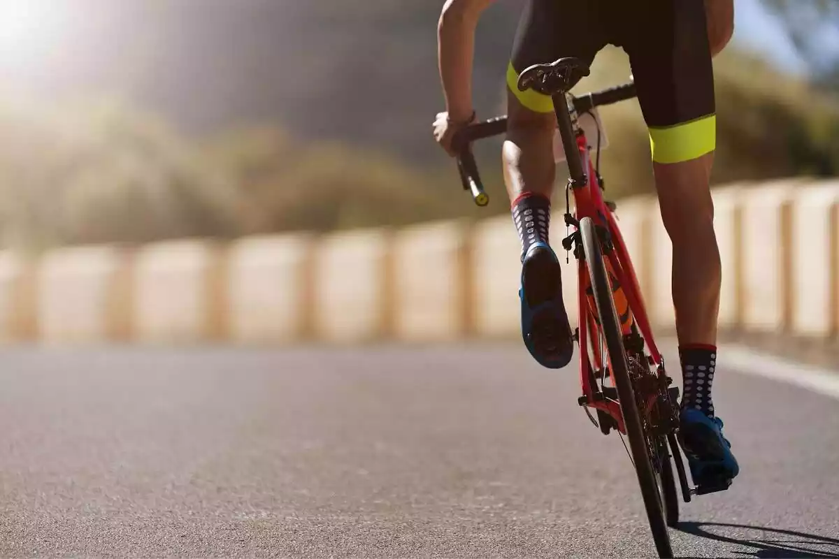 Plano corto de las piernas de un ciclista conduciendo una bicicleta por una carretera