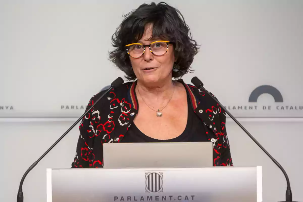 Mujer con gafas hablando en un podio del Parlamento de Cataluña.